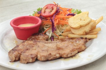 steaks and vegetable salad with french fries.