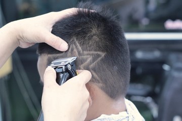 The boy's haircut with clipper and razor in the barber shop