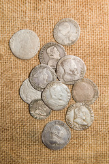 Ancient silver coins with portraits of kings on the old cloth