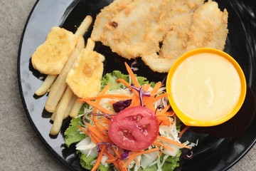 fish steaks and vegetable salad with french fries.
