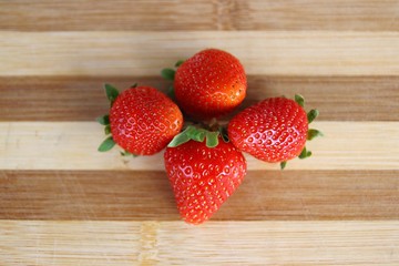 Four strawberries on the wooden tray
