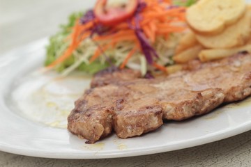steaks and vegetable salad with french fries.