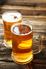 Two mug of beer on brown wooden background