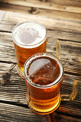 Two mug of beer on brown wooden background