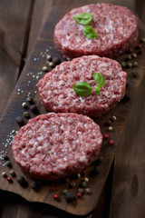 Raw beef cutlets with seasonings over rustic wooden background
