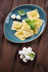 Italian ravioli stuffed with mozzarella over dark wooden surface
