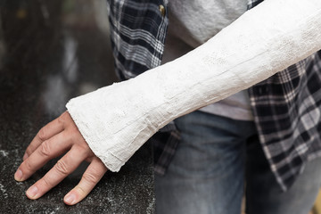 Fototapeta premium Mann lehnt mit eingegipsten Fingern an Küchenzeile