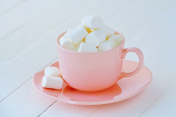Obraz na płótnie Canvas Porcelain pink cup full of white marshmallows