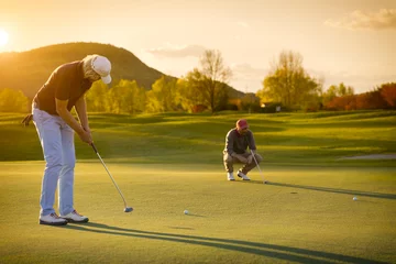 Photo sur Aluminium Golf Deux joueurs de golf senior au coucher du soleil.
