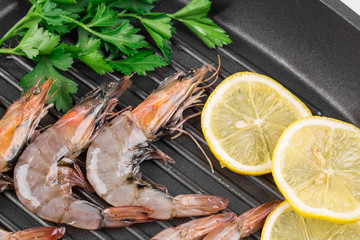 Raw shrimps on black pan.