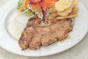 steaks and vegetable salad with french fries.