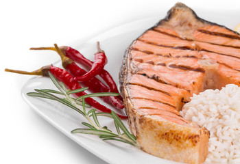 Grilled salmon steak with vegetables on plate.