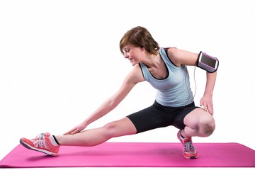 Pretty brunette stretching her leg on exercise mat 