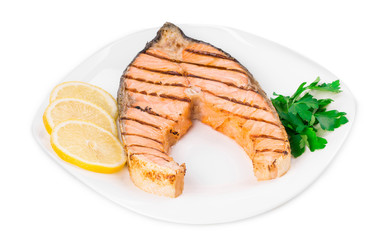 Grilled salmon steak with vegetables on plate.