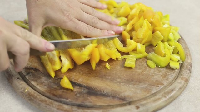 cutting yellow peppers over wooden chopping board