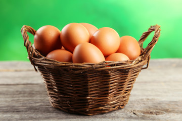 Chicken eggs in basket on grey wooden background