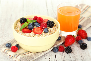 Oatmeal with berries on white wooden background