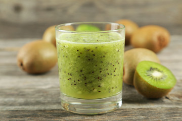 Fresh kiwi smoothie in glass on grey wooden baclground