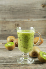 Fresh kiwi smoothie in glass on grey wooden baclground