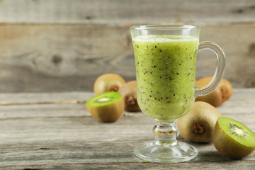 Fresh kiwi smoothie in glass on grey wooden baclground