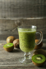 Fresh kiwi smoothie in glass on grey wooden baclground