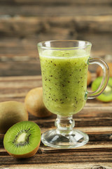 Fresh kiwi smoothie in glass on brown wooden baclground