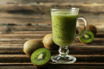 Fresh kiwi smoothie in glass on brown wooden baclground