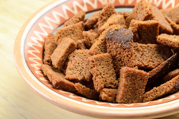 Rye bread croutons in a bowl on a wooden background