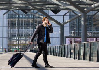 Man walking with suitcase and mobile phone at airport