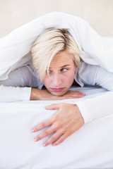 Fototapeta na wymiar Sad blonde woman lying on the bed