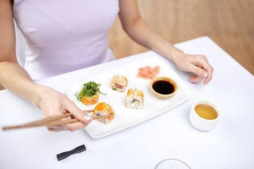 Obraz na płótnie Canvas close up of woman eating sushi at restaurant