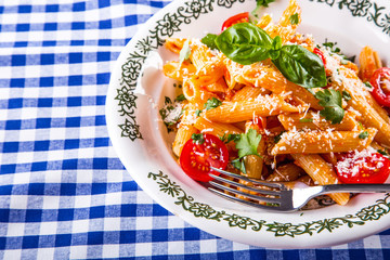 Plate with pasta pene cherry tomatoes basil leaves  