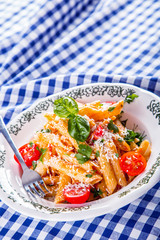 Plate with pasta pene cherry tomatoes basil leaves  
