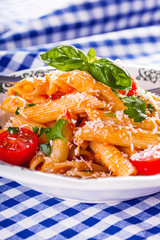Plate with pasta pene cherry tomatoes basil leaves  