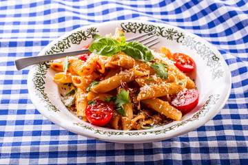 Plate with pasta pene cherry tomatoes basil leaves  