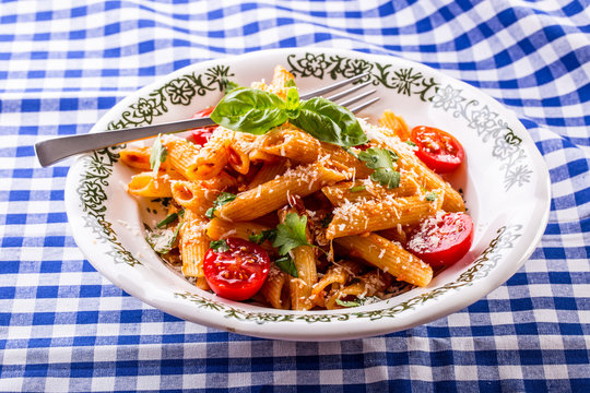 Plate with pasta pene cherry tomatoes basil leaves  