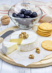 Soft brie cheese with crackers nuts and olives