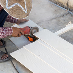 carpenter hands using electric saw on wood at construction site