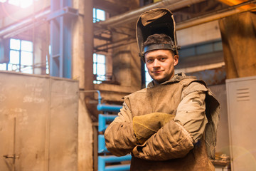 Young man with protective mask in a welding factory