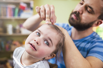 Young father styling hair of his daughter