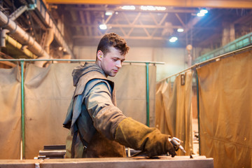 Young man in a factory preparing equipment for welding