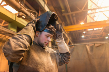 Young man with protective mask in a welding factory