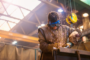 Young man with protective goggles welding in a factory - obrazy, fototapety, plakaty