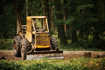 Naklejka premium Old tractor on the forest deforestation work