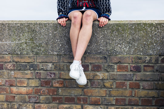 Young woman sitting on a brick wall