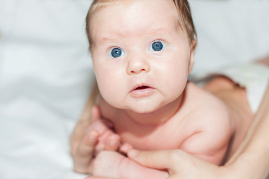 newborn baby girl lying on her stomach on a white bed