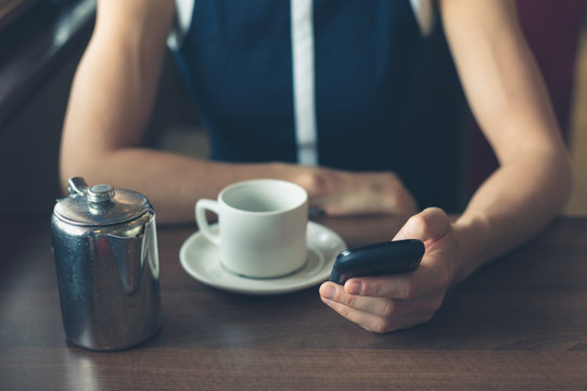 Woman having coffee and using smartphone