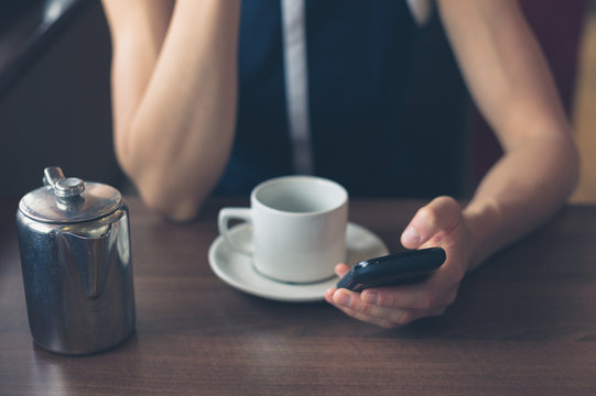Woman having coffee and using smartphone