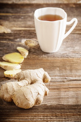 Ginger tea in a white cup on wooden background