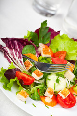 Gemischter Salat auf einem weißen Teller mit einer Gabel